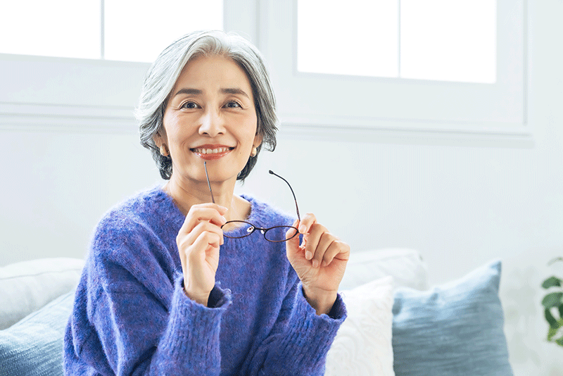 Asian woman removing her glasses in the living room.