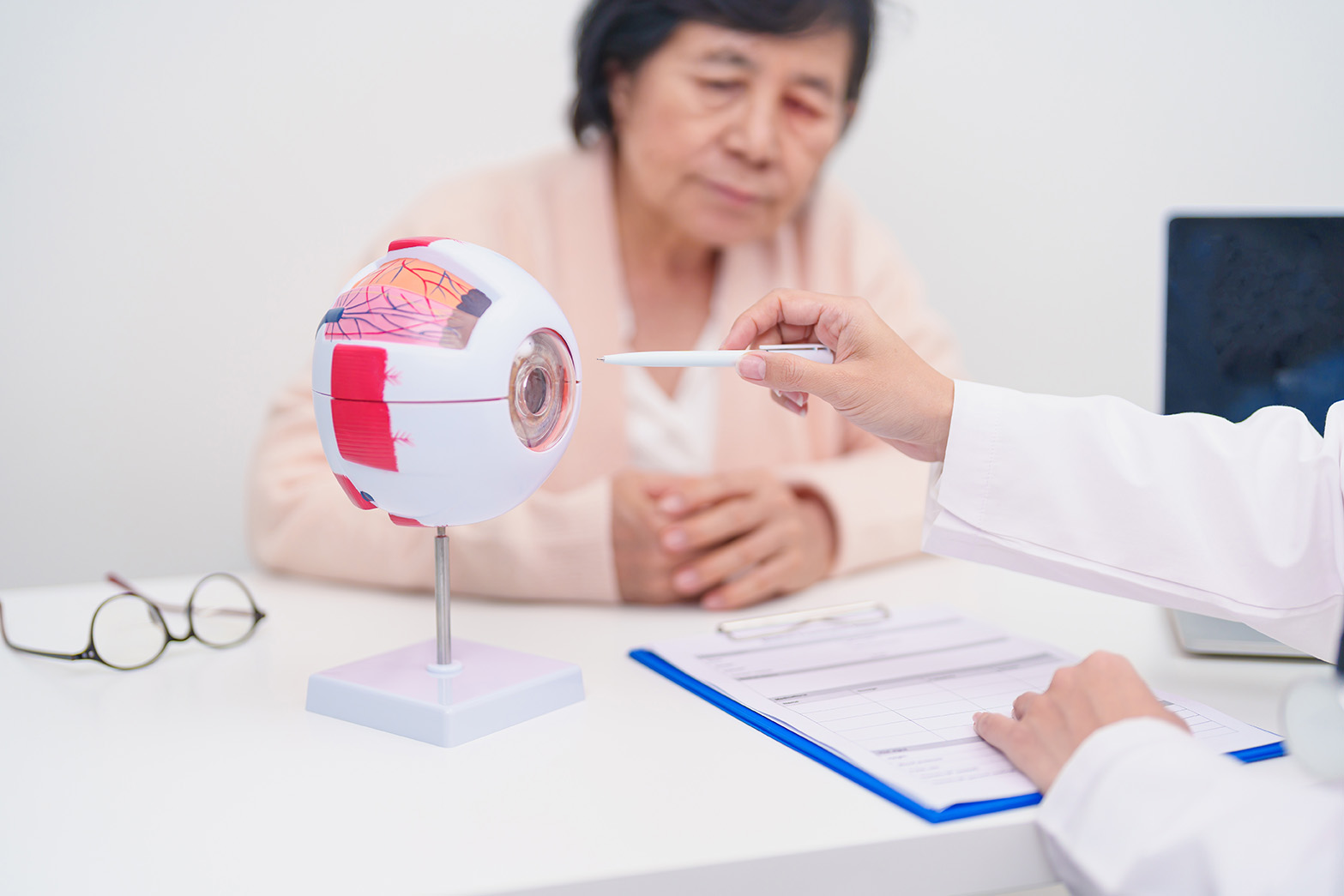 Doctor giving information to patient on eye model at eye specialist clinic